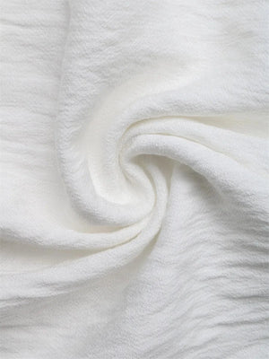 Vit crêppad blus med blommiga applikationer